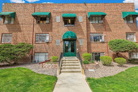 A red brick building with green awnings and a green door.