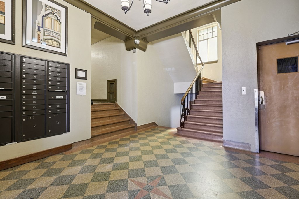 A hallway with a checkered floor and a staircase.