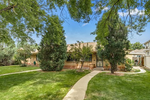 A house with a green lawn and trees in front.