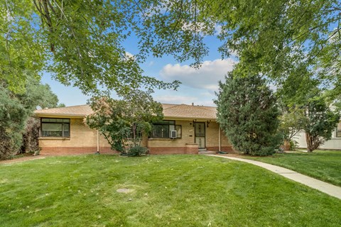 A house with a green lawn and trees in the front yard.