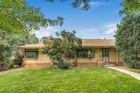 A house with a brown roof and a green lawn in front.