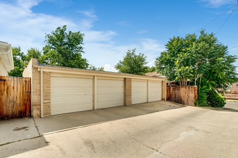 A row of garage doors are closed and the driveway is empty.