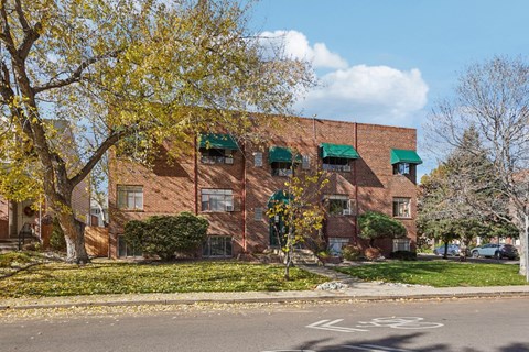 A red brick building with a green awning and a bike lane in front.