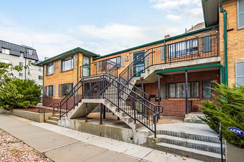 A brick building with a green roof and a staircase leading to the second floor.