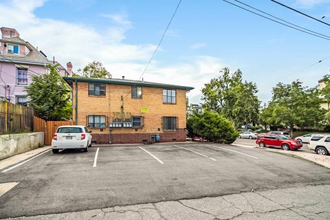 A parking lot with a white car parked in front of a brick building.