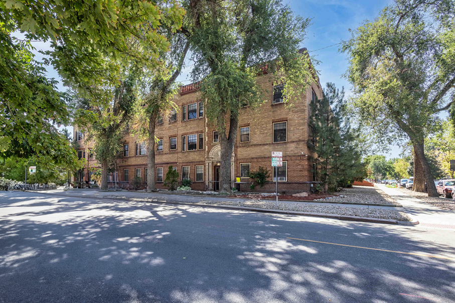 a brick building with trees in front of it on a street