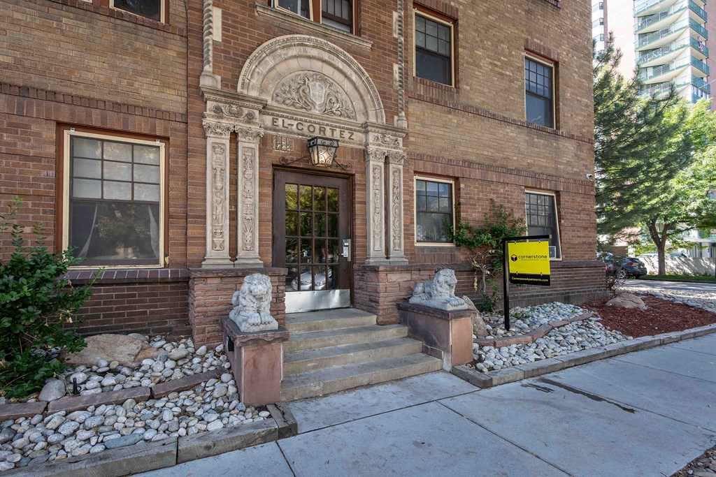 the front of a brick building with steps and a sidewalk