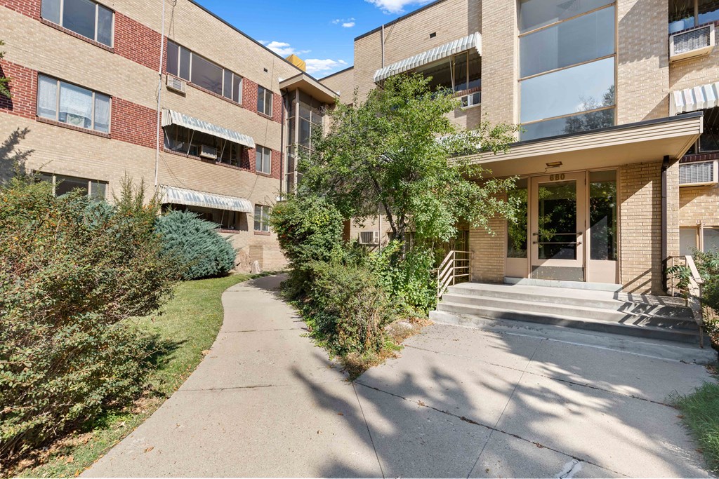 the entrance to an apartment building with a sidewalk in front of it