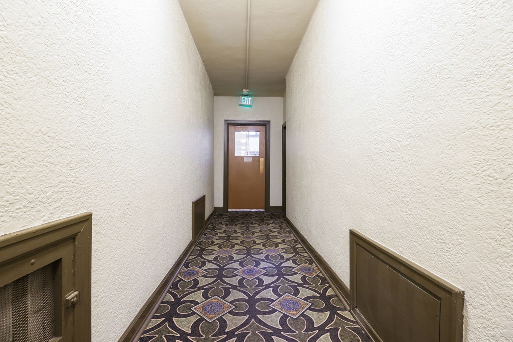 A hallway with a patterned floor and a door at the end.