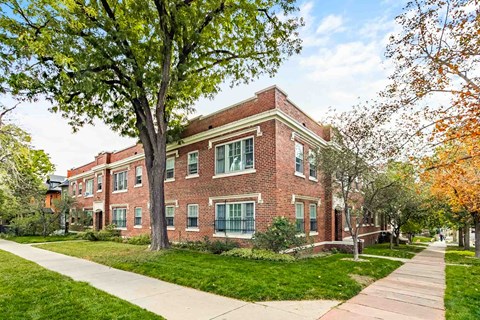 A red brick building with a tree in front of it.