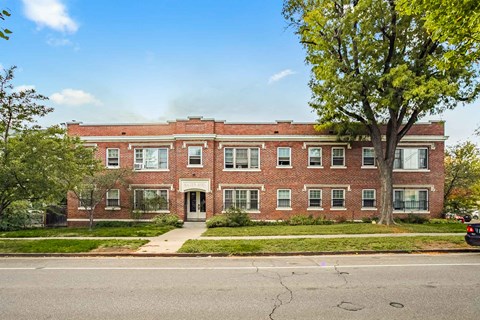 A red brick building with a tree in front.