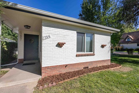 the front of a white brick house with a black door