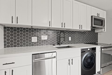 a black and white kitchen with white cabinets and a washing machine