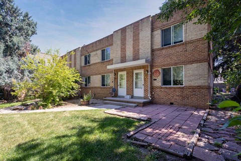 a brick building with a white door and a brick patio in front of it