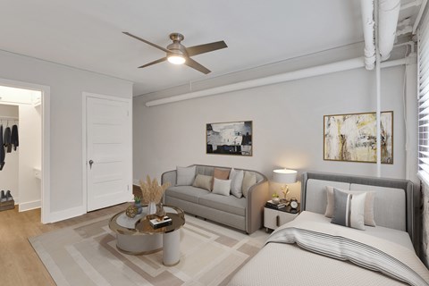 A well-lit bedroom with a bed, couch, and a ceiling fan.