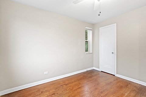 a bedroom with hardwood floors and a white door