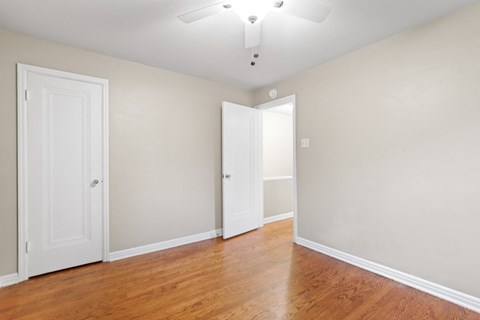 a bedroom with two doors and a ceiling fan