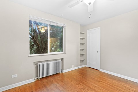 a bedroom with hardwood floors and a large window