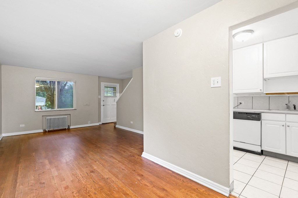 a kitchen and living room with white cabinets and a wood floor
