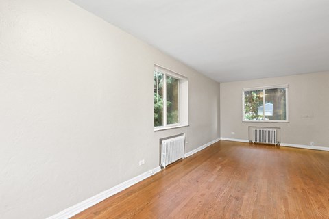 a bedroom with hardwood floors and two windows