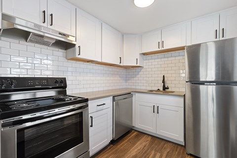 a white kitchen with stainless steel appliances and white cabinets