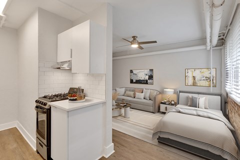 A modern kitchen with a stove top oven and a living room with a couch and a bed.