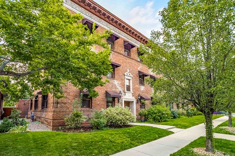 A red brick building with a tree in front of it.
