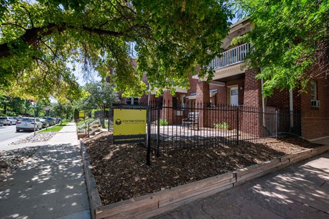 a sign in front of a fence with a building in the background