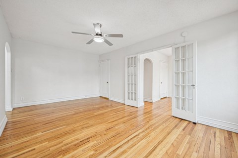 A room with a ceiling fan and wooden flooring.