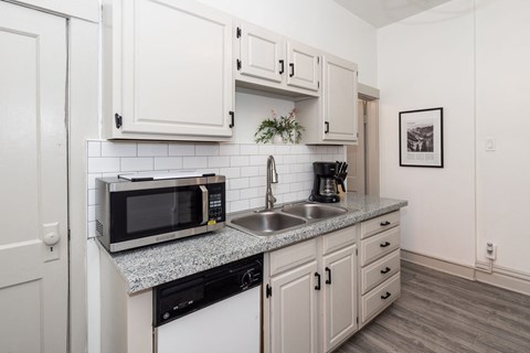 a kitchen with white cabinets and a sink and a microwave