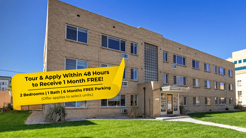 A building with a sign offering free parking for a month if you tour and apply within 48 hours.