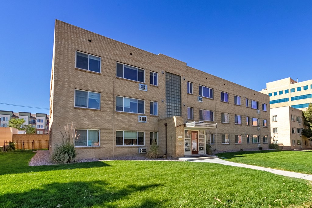 A large brick building with a green lawn in front.