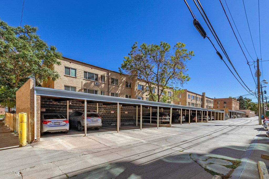 A parking garage with cars parked inside and a building in the background.