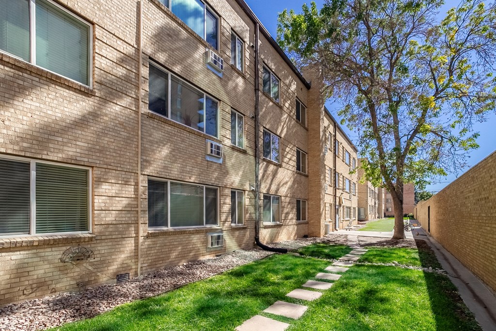 A brick apartment building with a tree in front.