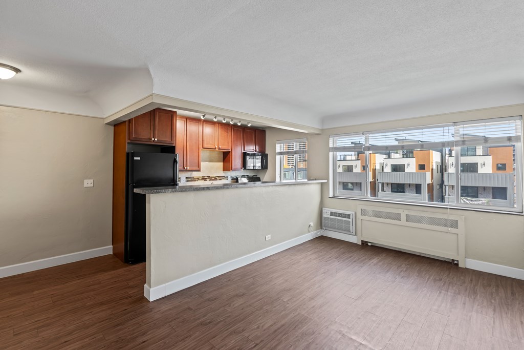 A spacious living room with a kitchen area and a view of the city.