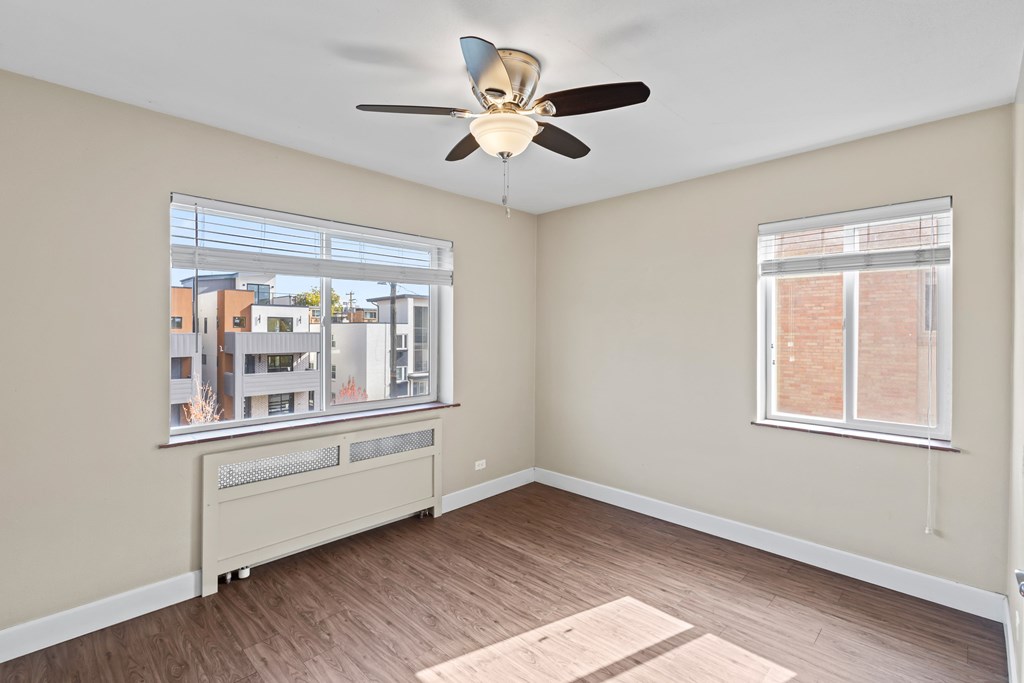 A room with a ceiling fan and two windows.