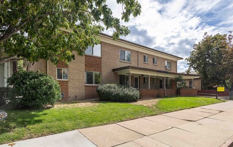 the front of a brick building with a sidewalk and grass
