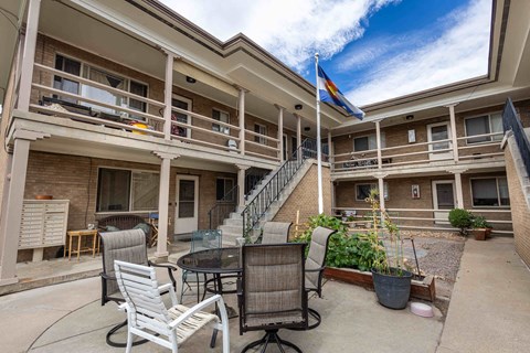 a patio with a table and chairs in front of a building