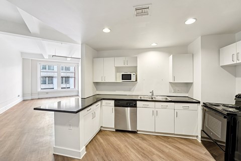 A modern kitchen with white cabinets and black countertops.