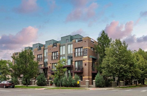 an apartment building on a street corner with trees