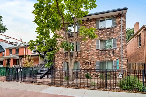 A brick building with a black fence in front.