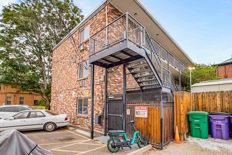 A brick building with a black gate and a bicycle leaning against it.