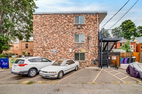 A white car is parked in front of a brick building.