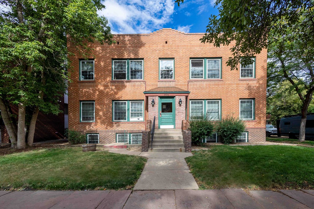 the front of a brick apartment building with a green door