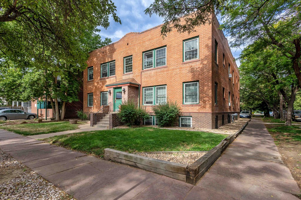 a brick building with green grass and trees in front of it