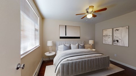 A bedroom with a large bed, a ceiling fan, and two lamps.