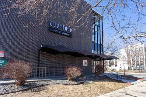 A building with a sign that says "Aperture Apartments" on it.