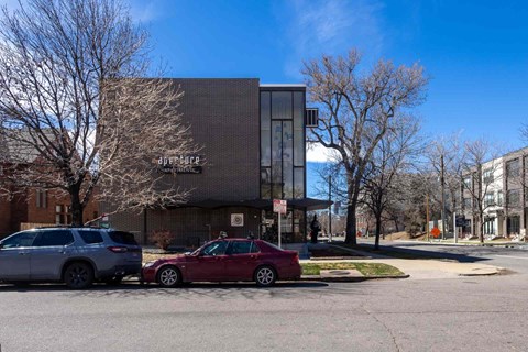 A red car is parked in front of a building with the sign "downtown.".