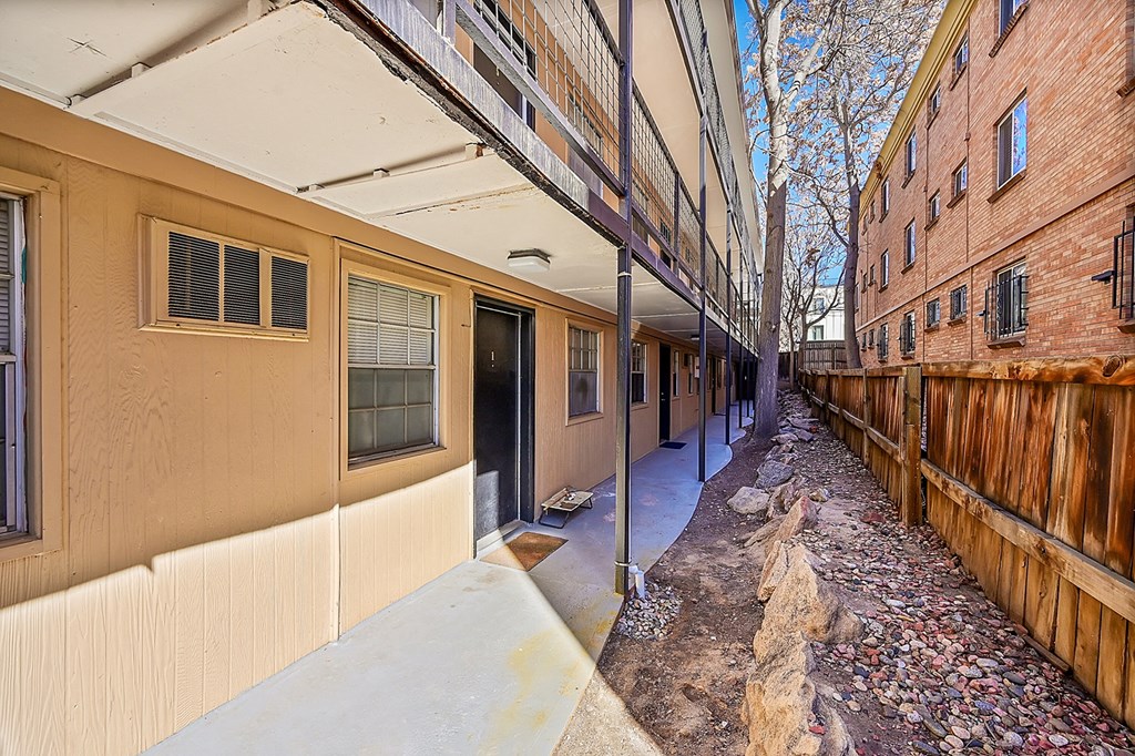an empty alleyway between two brick buildings with a wooden fence