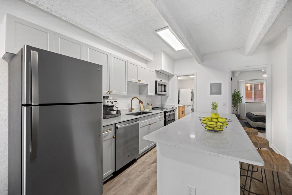 A modern kitchen with a black refrigerator and a bowl of fruit on the island.